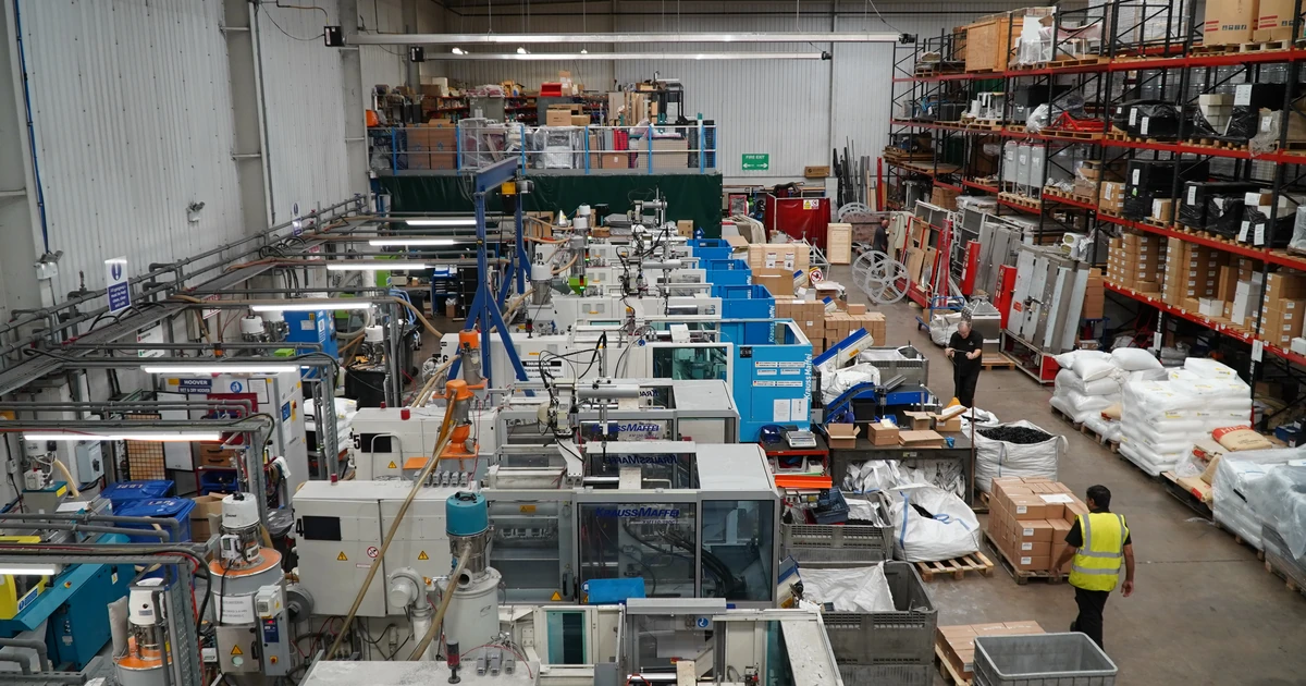 Interior view of Thermoseal Group manufacturing facility with machinery and two workers in high-visibility vests
