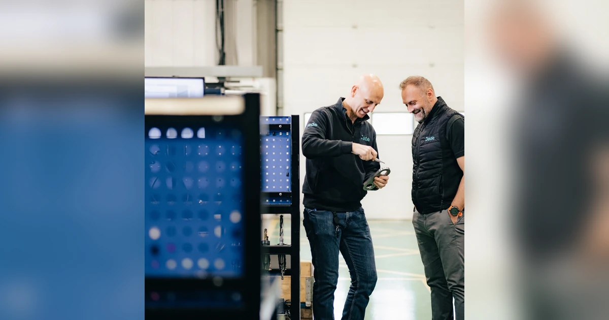 Two men in Jade Engineering branded clothing examining a product component inside a workshop