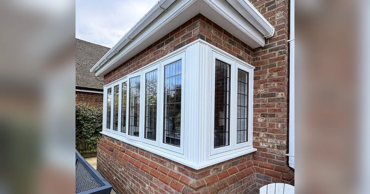 Close-up of Residence 9 white woodgrain timber windows with square leaded glass on a red brick home corner