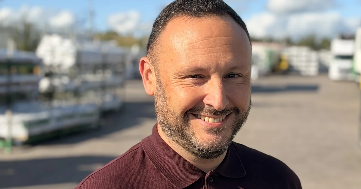 Danny Cavanagh smiling at an outdoor depot site under a blue sky