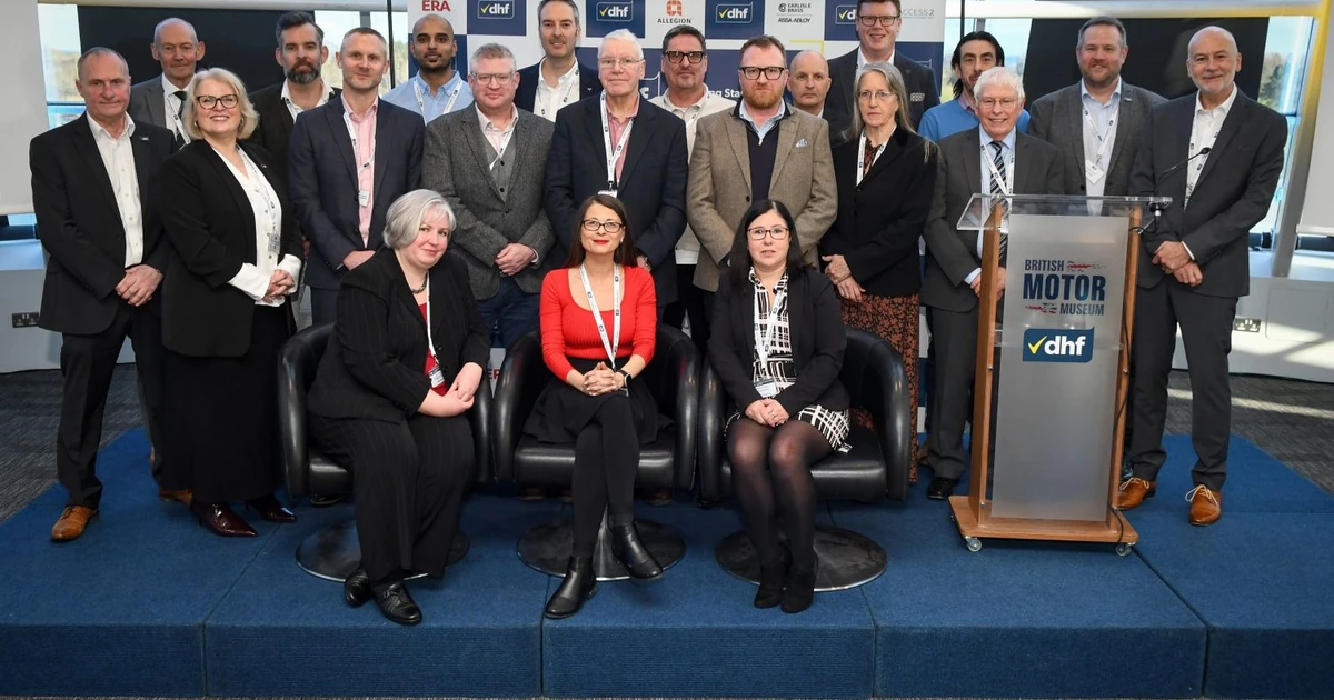 Large group of industry professionals standing and sitting on a stage with DHF banners in the background, indicating collaboration on the DHF Building Hardware Training Programme