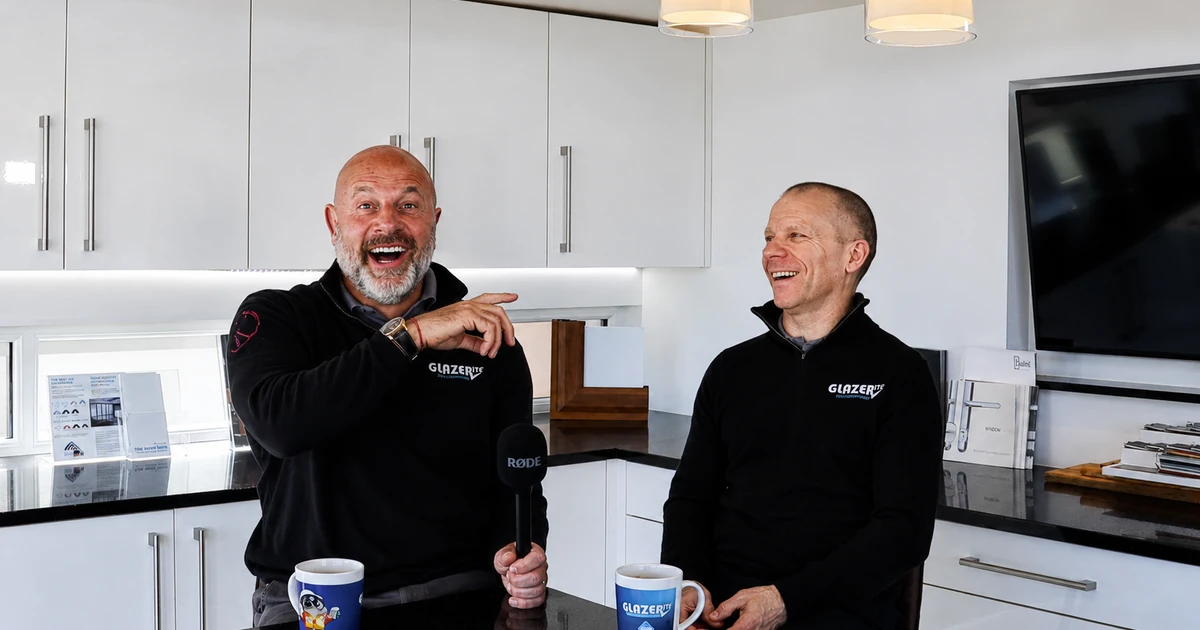 Rob Brearley and Darren Rhodes in a modern office kitchen area, smiling and engaged in conversation with company-branded mugs