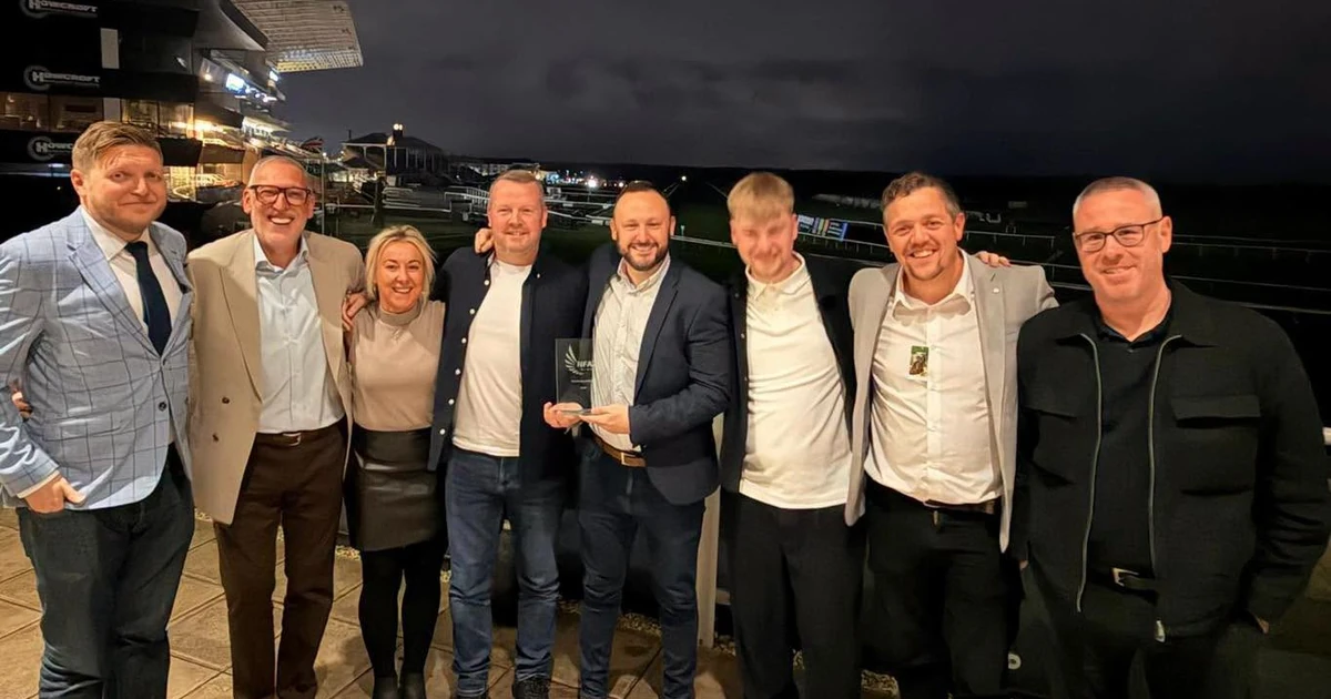 Eight people standing outdoors at night, one holding an award, celebrating GAP's Trade Counter of the Year win