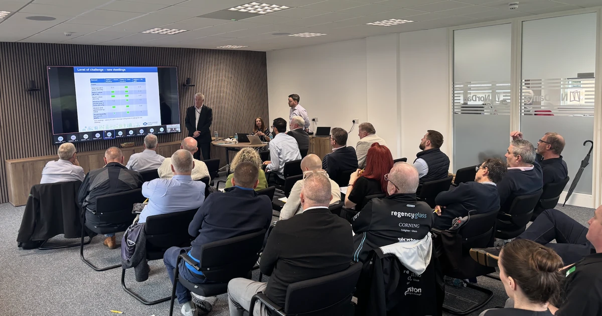 Group of around 24 GGF members attending a presentation in a conference room with a large screen displaying energy standards information