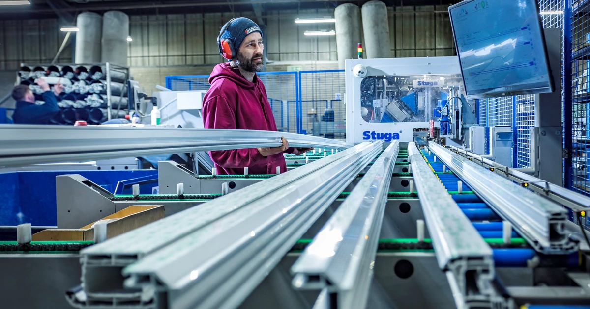 Man operating cutting machinery with long white profiles at Heritage Trade Frames factory
