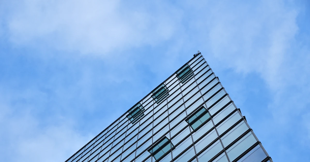 Modern glass office building facade with blue sky background