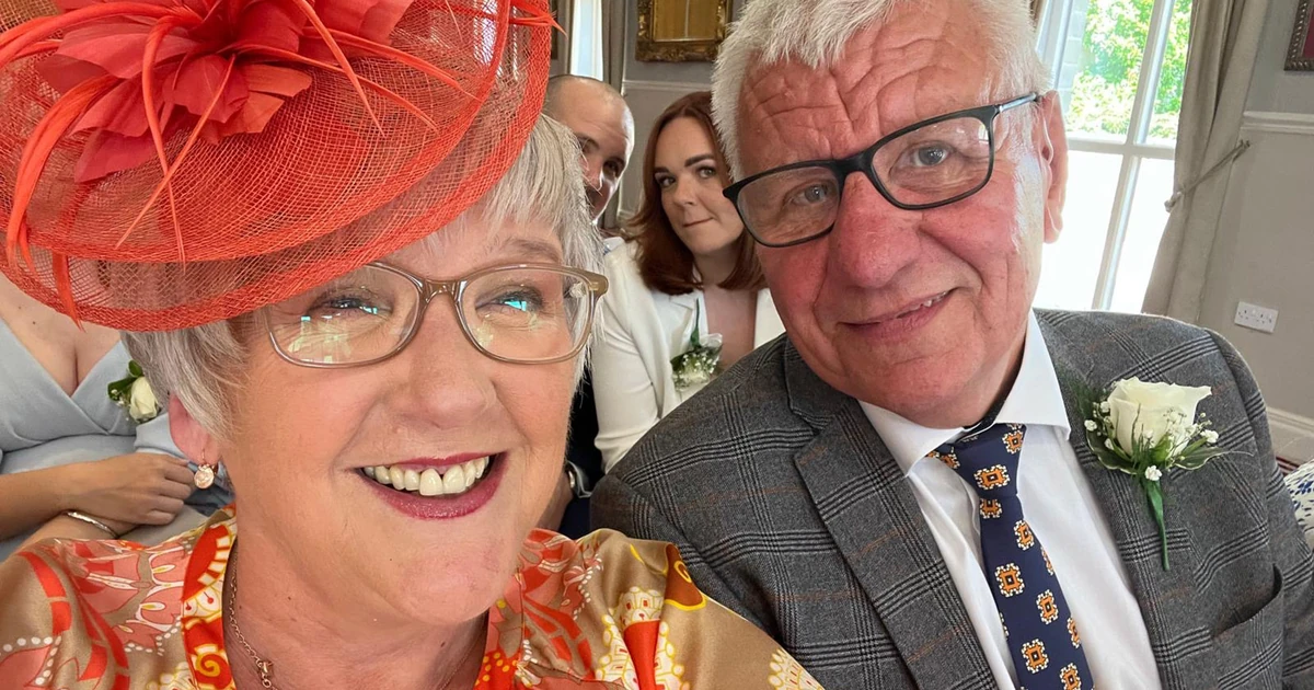 Karen Starkey and Gerry Starkey smiling closely together indoors, dressed in formal attire