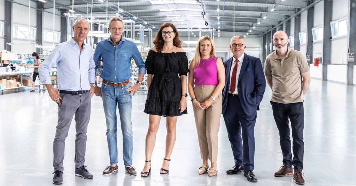 Six senior team members from Pellini and Morley Glass standing in a bright factory setting, representing the partnership between the companies.