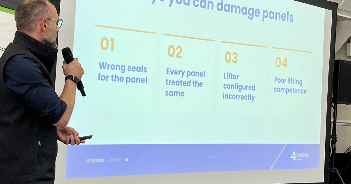 Tom Spence speaking with microphone in front of a screen showing text about four ways to damage panels