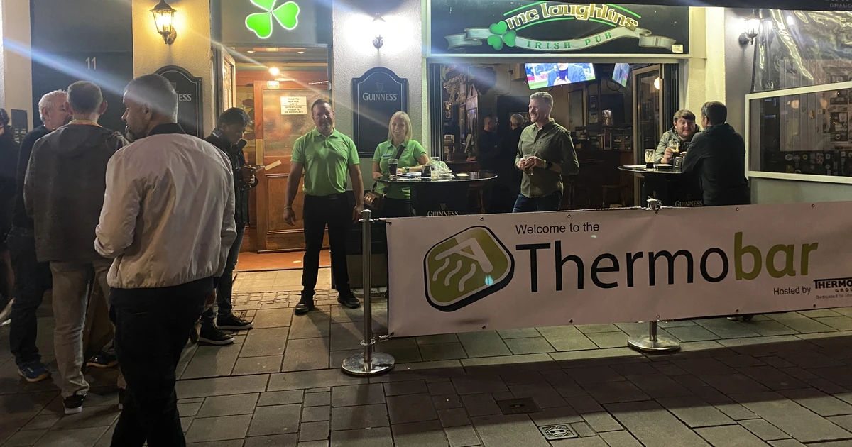 People gather outside McLaughlin’s Irish Bar in Düsseldorf with a ThermoBAR welcome banner displayed during the event