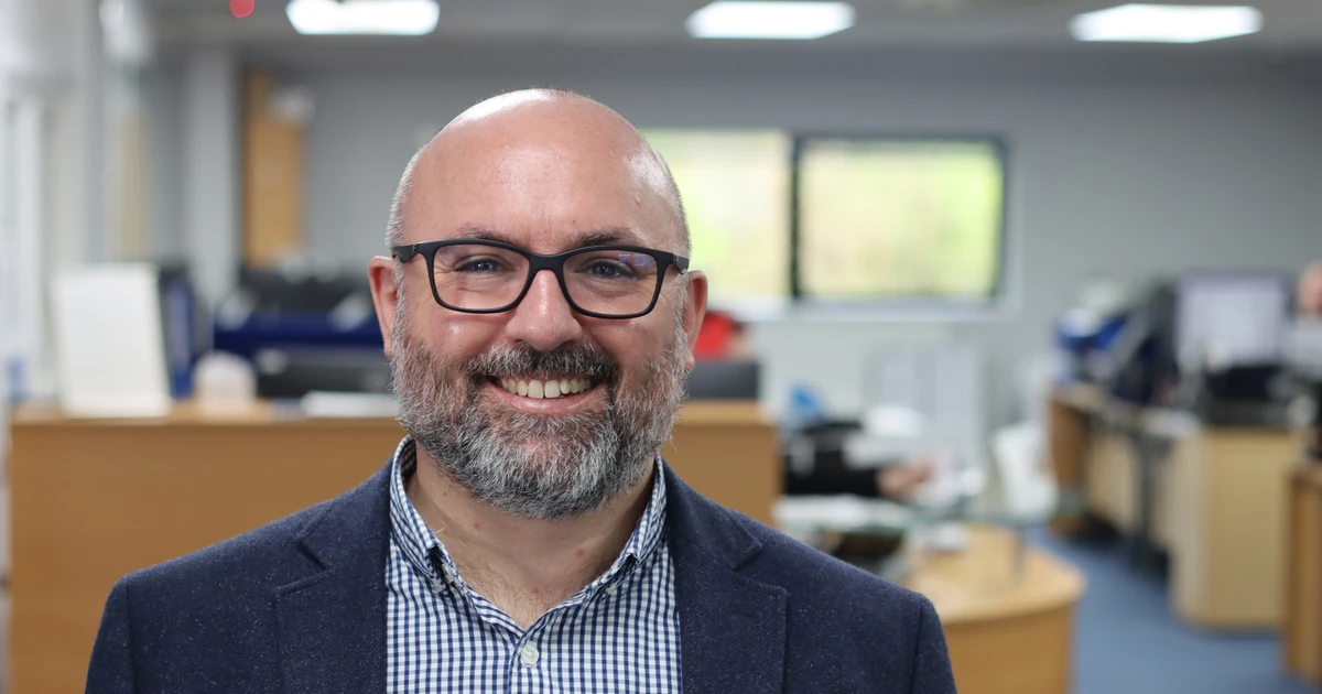 smiling man with glasses and beard in office environment